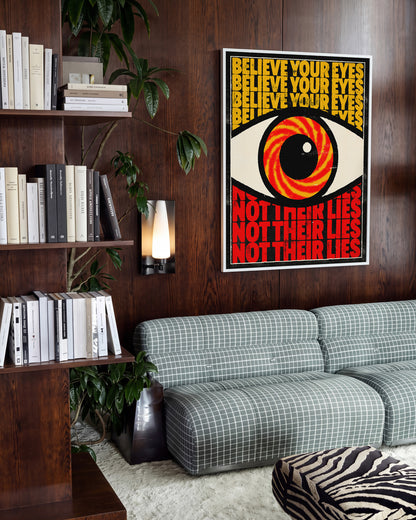 Believe Your Eyes psychedelic quote poster in a white frame on a wall